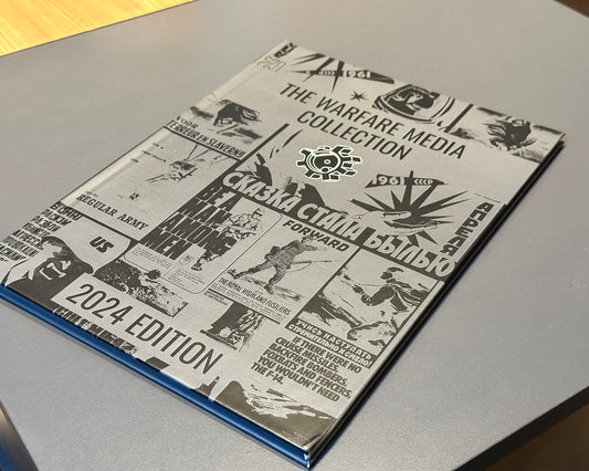 A book titled "The Warfare Media Collection - Photo Book" by Warfare Media lies on a table. The cover, a visual exploration, features various grayscale images and texts related to military and warfare, including Cold War propaganda posters and symbols.