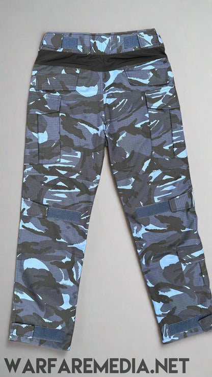 A pair of Warfare Media OPFOR DPM Trousers (G3 Cut) with a blue and gray camouflage pattern is laid flat on a brick pavement. The pants, ideal for tactical training, feature multiple pockets and are folded to show the front view.