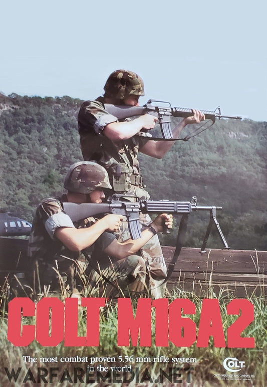 Two soldiers dressed in camouflage gear, with one kneeling and aiming a Colt M16A2 rifle while the other stands and aims the same rifle. They are in a grassy outdoor setting with hills in the background. The text reads "Colt M16A2: The most combat-proven 5.56 mm rifle system in the world." This captivating image is available as high-quality posters on semi-glossy paper under the product name "Colt M16A2 Sales Ad" by Warfare Media.