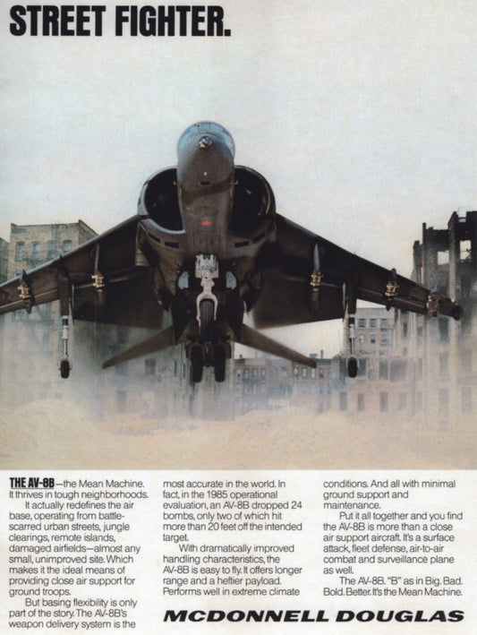 A military jet, the AV-8B HARRIER 2 "Street Fighter," is showcased in front view on an urban street with damaged buildings. The text emphasizes its versatility and maneuverability on durable prints, making it ideal for combat environments. The Warfare Media logo is visible on high-quality posters featuring semi-glossy paper for added durability.